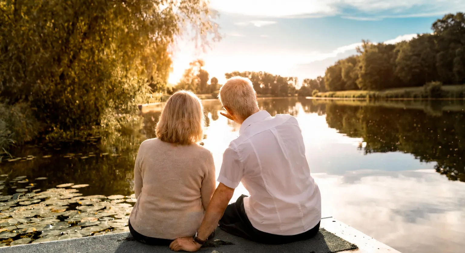 Couple disutant sur un ponton devant un &eacute;tang