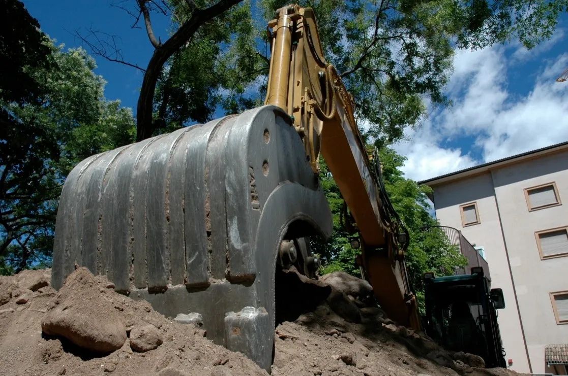 Le godet d'une excavatrice creusant un tas de terre sur un chantier.