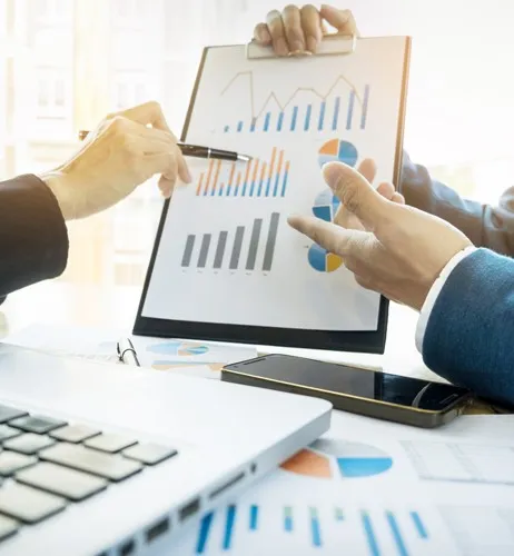 Des professionnels analysent ensemble des graphiques financiers et de performance pr&eacute;sent&eacute;s sur un porte-bloc.