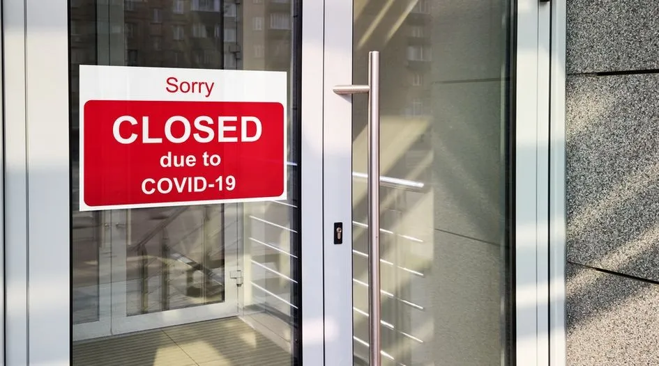Une affiche rouge indiquant &laquo; CLOSED due to COVID-19 &raquo; est coll&eacute;e sur la porte vitr&eacute;e d'un &eacute;tablissement ferm&eacute;.