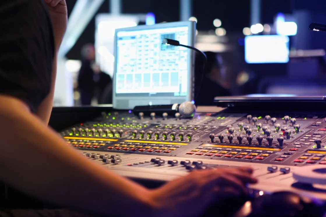 Une r&eacute;gie de contr&ocirc;le avec une console de mixage audio et des &eacute;crans