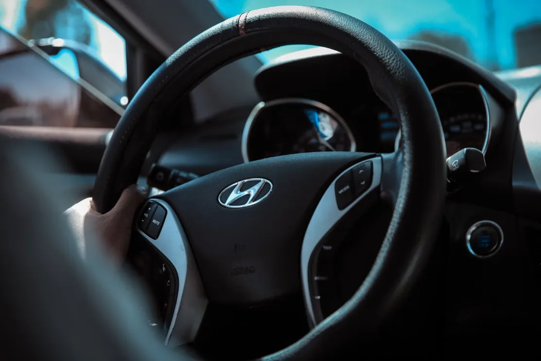 Une main tient le volant d'une voiture de marque Hyundai