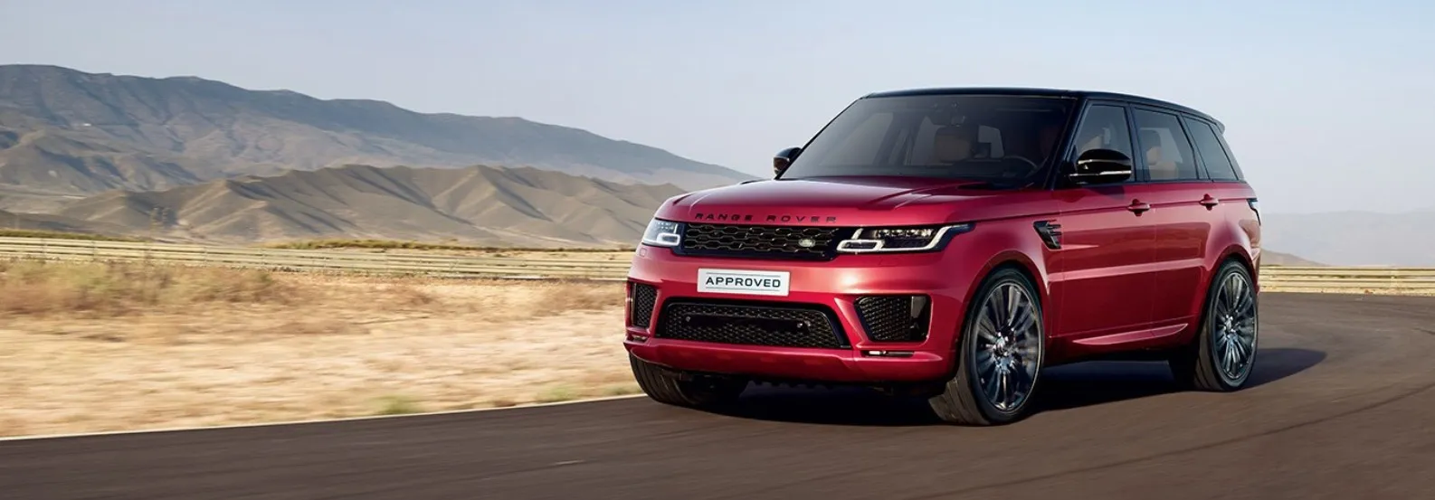 Un SUV Range Rover rouge circulant sur une route de montagne.