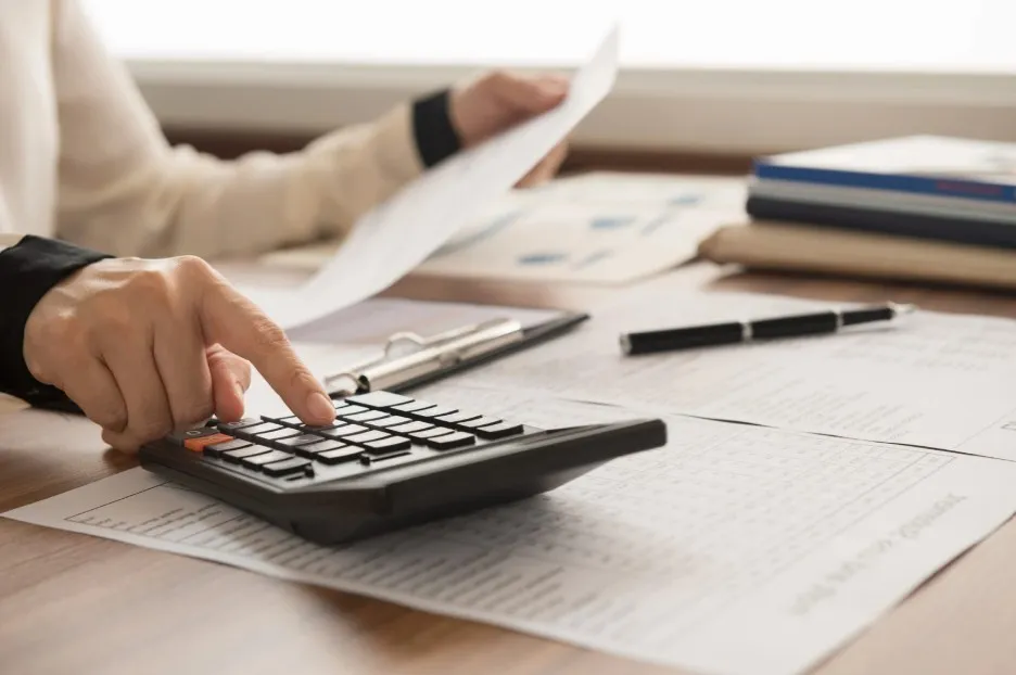 Une personne utilise une calculatrice pour analyser des documents
